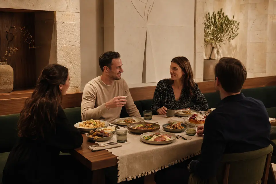 Felnőtt vendégek közös vacsorán egy meleg tónusú, kortárs éttermi térben